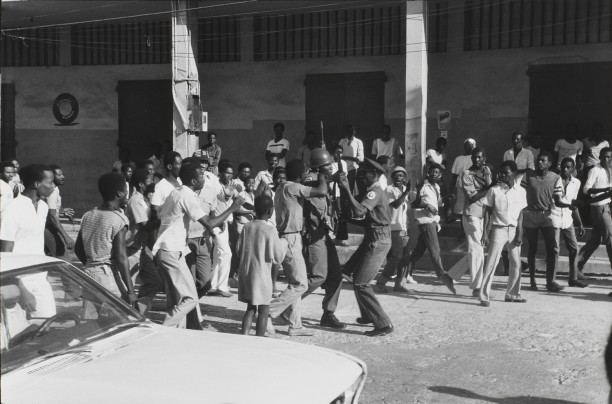 Dawn on February 7th.  As news spreads that Jean-Claude Duvalier is gone, a soldier disarms a Tonton Macoute
